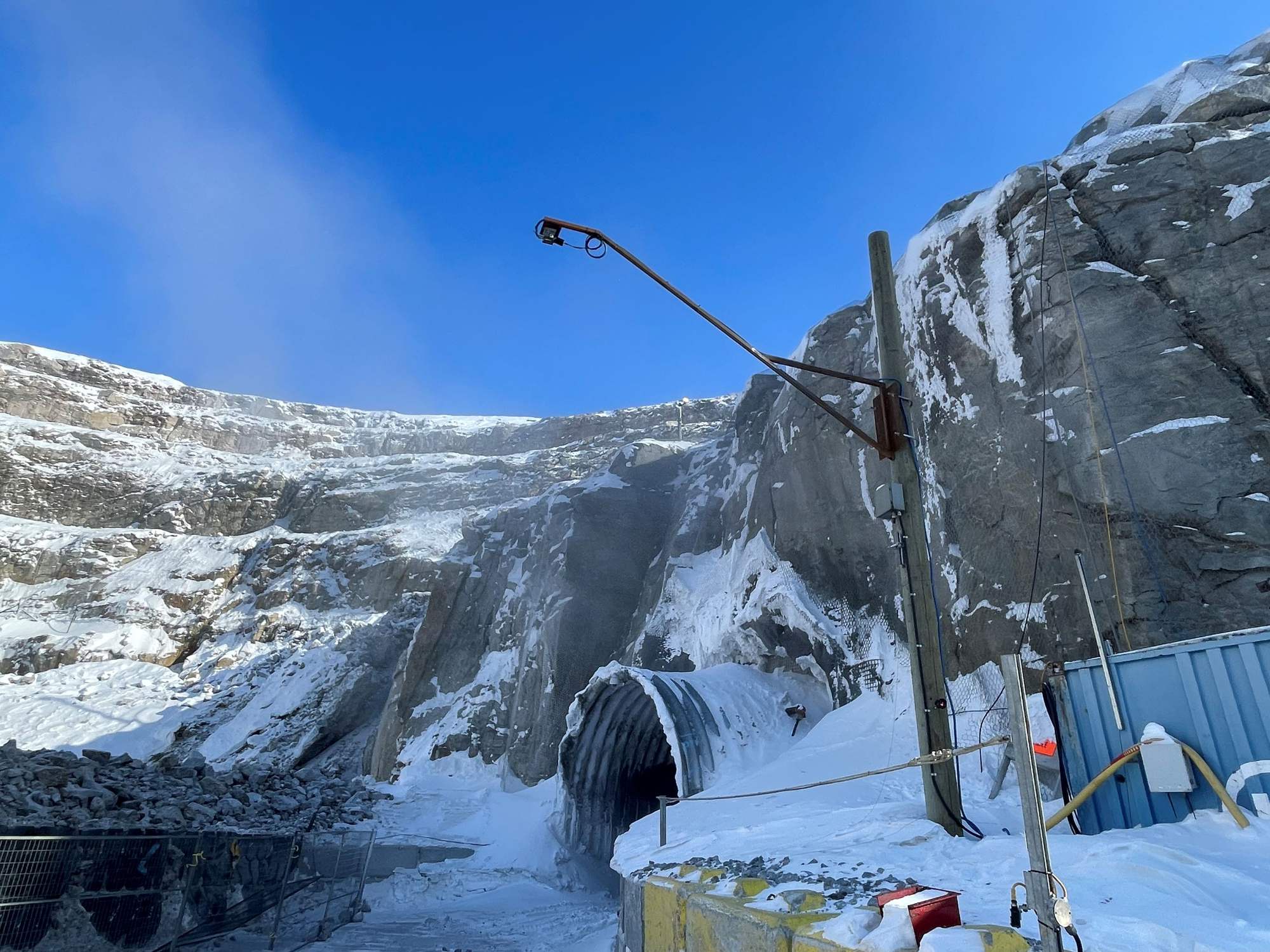 Scanner mounted on a pole above the haul road at a snow-covered mine portal